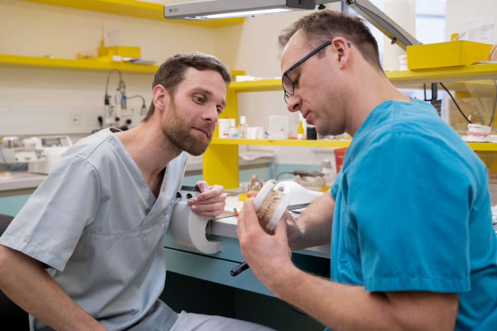 Zahntechniker im Gespräch - Zahnarzt und Zahntechnikermeister begutachten gemeinsam ein Gipsmodell.